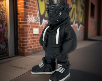 Peut inclure: Figurine de dragon noir portant un sweat à capuche noir, une salopette et des baskets avec des accents blancs. Le dragon a les yeux verts et se tient sur un trottoir devant un mur de briques avec des graffitis.