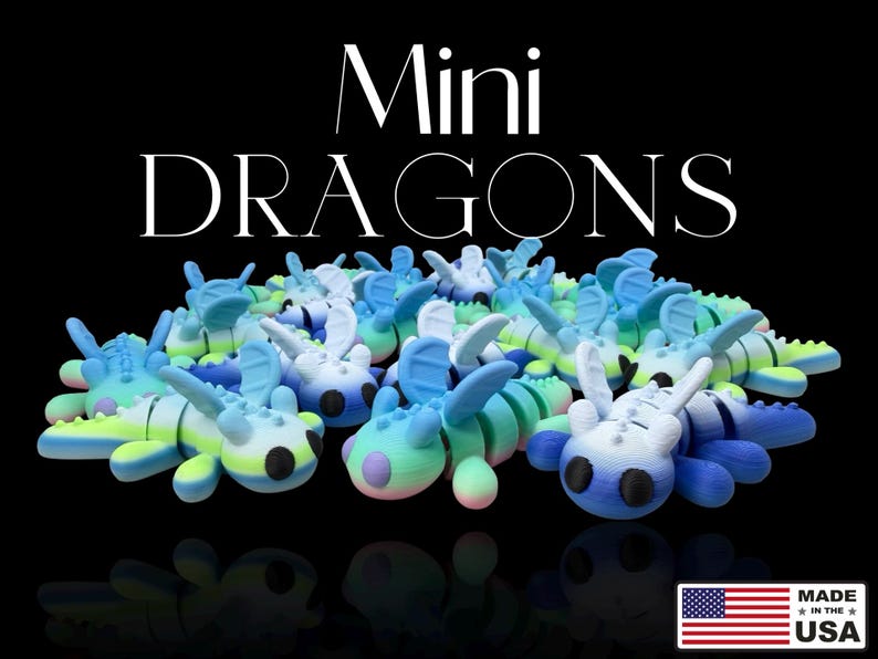 Op de afbeelding: Een verzameling kleurrijke mini-drakenfiguren in blauw, groen en wit, met de tekst "Mini Dragons" in het wit. De figuren staan op een zwarte achtergrond. Gemaakt in de VS.