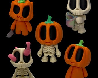 Peut inclure: Plusieurs figurines sur le thème d'Halloween. Les figurines comprennent des têtes de citrouille orange, un squelette et un personnage en forme de crâne. Une figurine de citrouille tient un couteau. Les figurines sont sur fond noir.