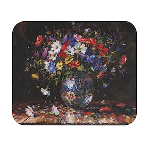 Può includere: Una vivace composizione floreale in un vaso a sfera da discoteca. Il bouquet presenta un mix di fiori rossi, bianchi, blu, gialli e viola. Lo sfondo è scuro e i fiori sono su una superficie di legno.