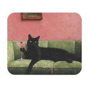 May include: A black cat with yellow eyes reclines on a green velvet sofa, holding a pink martini with an olive. The background features a pink wall and a framed picture, creating a whimsical scene.