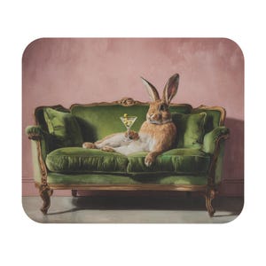May include: A whimsical image of a brown rabbit lounging on a green velvet sofa, holding a martini glass with olives. The sofa has gold trim and is set against a pink background. The rabbit is the focal point of this decorative art.
