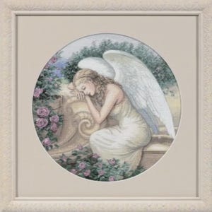 May include: Framed artwork depicting a peaceful angel in a white gown with large white wings, resting on a stone ledge. The artwork is set within a circular frame, surrounded by pink roses and greenery, with a cream-coloured frame.