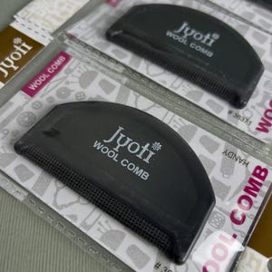May include: Several black Jyoti Wool Combs in their original packaging. The combs are semi-circular with fine teeth and the brand name printed in white. The packaging includes the text "Wool Comb" and the product number #36371.