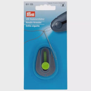 May include: A Prym LED needle threader in retail packaging. The device is dark gray with a bright green button and a thin metal needle. The blue card features the text 611 125, Prym, LED Nadeleinfädler, Needle threader, and Enfile-aiguille.