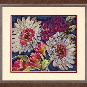 Puede incluir: Un bordado en punto de cruz enmarcado que presenta un arreglo floral con dos grandes margaritas gerbera blancas, un crisantemo morado oscuro y flores más pequeñas rojas y amarillas con hojas verdes sobre un fondo azul oscuro.