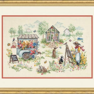 Puede incluir: Un bordado en punto de cruz enmarcado que representa una escena de jardín con un carrito de flores, un invernadero, una persona pintando en un caballete, dos perros, dos conejos y mariposas. Un letrero dice "WELCOME OPEN".