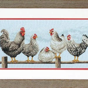 Puede incluir: Un bordado en punto de cruz enmarcado que representa cuatro gallinas posadas sobre una valla de madera con un fondo azul claro. Las gallinas tienen plumaje moteado en gris, blanco y negro con crestas rojas. La obra está en un marco marrón.