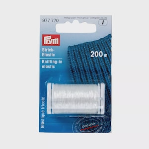 Può includere: Una bobina di elastico da maglieria bianco su un cartoncino blu con l'etichetta Prym 977 770. La confezione riporta la scritta 200 m e presenta un'illustrazione di tessuto a maglia blu. Il prodotto è destinato a progetti di cucito e tessili.