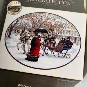 Puede incluir: Un kit de punto de cruz titulado The Gold Collection Winter Impressions que muestra una escena nevada con un carruaje de caballos. El diseño ovalado muestra figuras con ropa de época, incluida una persona con abrigo rojo, en un paisaje invernal.