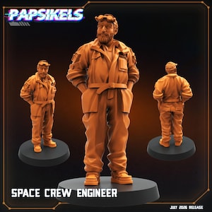 May include: An orange miniature figurine of a space crew engineer with a beard, wearing a jumpsuit with pockets, a belt, and goggles on the forehead. The figure stands on a circular black base. Text reads PAPSIKELS, SPACE CREW ENGINEER, JULY 2026 RELEASE.