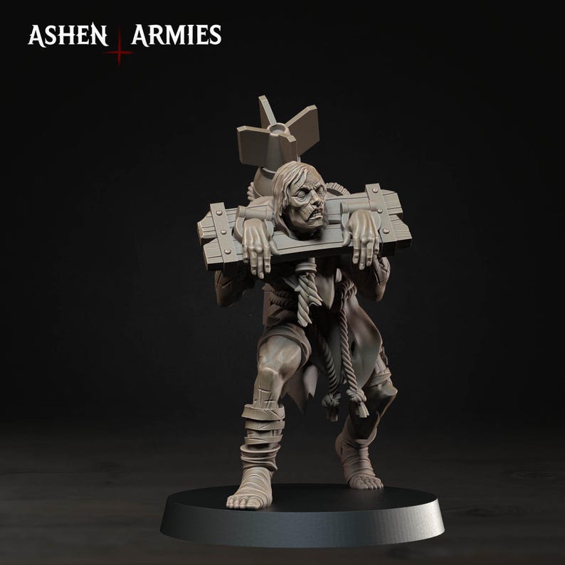 Pode incluir: Uma miniatura cinzenta da Ashen Armies representando uma pessoa presa num pelourinho de madeira. A figura tem cabelo comprido, veste roupas esfarrapadas com detalhes em corda e carrega um objeto grande tipo bomba nas costas sobre uma base.