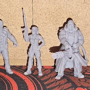 May include: A collection of eight unpainted gray miniature figures standing in a row. The set includes various human characters in tactical gear, some holding rifles or pistols, one accompanied by a small dog, and one figure mounted on a motorcycle.