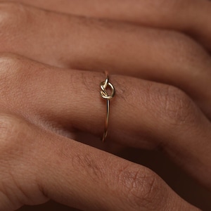 Könnte beinhalten: Ein Set aus drei Keramikbechern mit gesprenkelter, matter Oberfläche. Die Becher sind in Creme-, Hellgrau- und Dunkelgrautönen gehalten. Jeder Becher hat ein schlichtes, modernes Design und einen abgerundeten Griff.