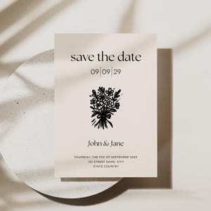 May include: Save the date card featuring a black and white illustration of a bunch of flowers. The text reads "save the date" with the date "09/09/29" underneath. The names "John & Jane" are printed below the date, followed by the date and location of the event: "THURSDAY, THE 9TH OF SEPTEMBER 2029, 123 STREET NAME, CITY, STATE COUNTRY".