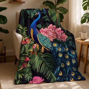 May include: A black throw blanket featuring a detailed embroidered peacock design. The peacock is blue, teal, and gold, surrounded by pink and red flowers and green foliage. The blanket is draped over a beige armchair.