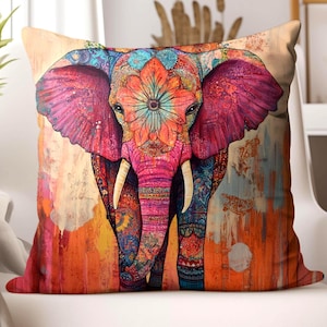 May include: A decorative square pillow featuring a colorful elephant design. The elephant is depicted with intricate patterns in shades of pink, orange, blue, and purple. The pillow has a textured appearance, with a warm, artistic background.