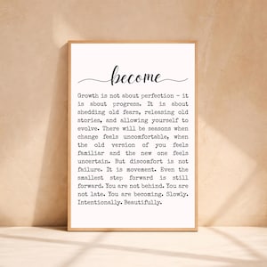 Pode incluir: Impressão emoldurada com a palavra "become" em escrita elegante acima de uma citação motivacional. A citação está em texto preto sobre um fundo branco, dentro de uma moldura de madeira castanho claro. A mensagem incentiva o crescimento pessoal.