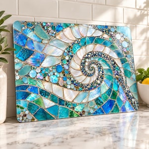 May include: A rectangular glass cutting board featuring a vibrant mosaic design of a spiral shell. The surface is composed of iridescent white, turquoise, and deep blue glass tiles and shell fragments arranged in a swirling, wave-like pattern.