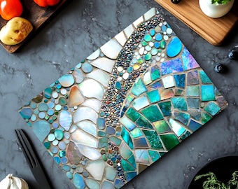 May include: A rectangular cutting board featuring a mosaic surface composed of iridescent abalone shell fragments in shades of white, teal, blue, and green, arranged in a pattern of varying shapes and sizes with a central band of small pebbles.