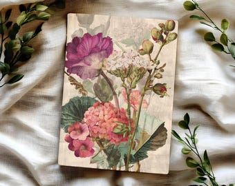 May include: A rectangular wooden plaque featuring a botanical illustration of various flowers including a large deep purple bloom, a cluster of pink hydrangea-like blossoms, and green foliage on a light beige background with a vintage texture.