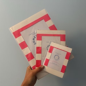 Könnte beinhalten: Eine Sammlung von Bilderrahmen mit weiß-rosa gestreiftem Rand. Die Rahmen sind in verschiedenen Größen erhältlich und tragen den Text "Crafty for Something Good". Die Rahmen werden von einer Person in der Hand gehalten.