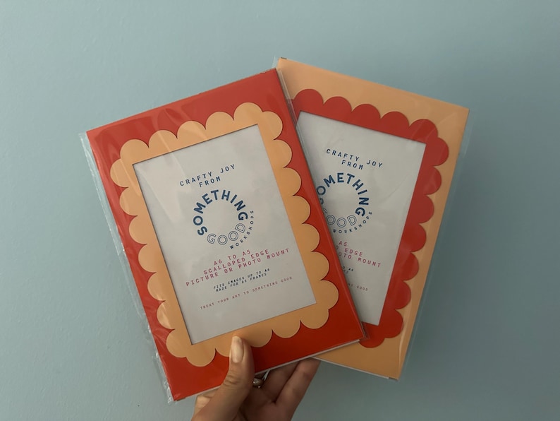 May include: Two rectangular picture frames with scalloped edges. One frame is red with a peach-colored interior, and the other is peach with a red interior. Each frame has the text "Crafty Joy From Something Good Workshop" and "A4 to A5 Scalloped Edge Picture or Photo Mount."