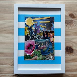 May include: A framed collage with a white border and blue and white striped accents. The artwork features a variety of images, including figures, flowers, and text. The word "SOMETHING" is visible in a yellow circle.