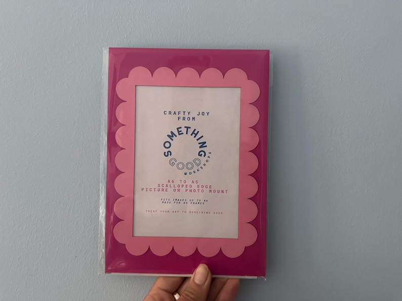 May include: A pink scalloped edge picture or photo mount with the text "Crafty Joy From Something Good Workshop". The frame is in a clear plastic sleeve. The frame fits 5x7 inch photos.