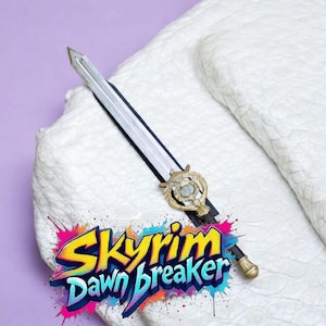 Puede incluir: Una espada decorativa con una hoja plateada y una empuñadura dorada, sobre una superficie blanca texturizada. La espada tiene un mango negro y está acompañada de un logotipo colorido que dice "Skyrim Dawnbreaker".