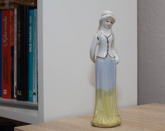 Figurka starej porcelany przedstawiająca elegancką kobietę w kapeluszu