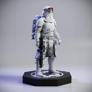 Può includere: Una statuetta di soldato in armatura bianca in piedi su una base esagonale nera con un emblema circolare. Il personaggio indossa un casco con occhiali arancioni, un cappotto bianco testurizzato e uno zaino, tenendo un fucile blaster nero.
