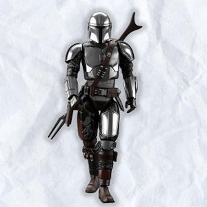 May include: A detailed action figure of The Mandalorian, clad in silver and black armor. The figure is holding a blaster pistol and a spear-like weapon. The figure has a brown leather strap across the chest and a helmet with a T-shaped visor.