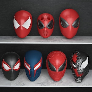 Könnte beinhalten: Eine Sammlung von sieben Superheldenmasken, hauptsächlich in Rot, Schwarz und Blau. Die Masken weisen verschiedene Designs auf, darunter die ikonische Spider-Man-Maske und andere von Charakteren inspirierte Designs. Die Masken werden auf Regalen vor dunklem Hintergrund präsentiert.