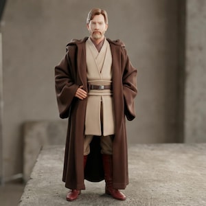 May include: A detailed action figure of a character from a science fiction franchise. The figure is dressed in a brown robe with a tan tunic and pants, a brown belt, and red boots. The figure has a beard and short brown hair.