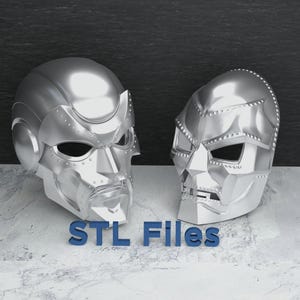 Könnte beinhalten: Zwei silberne 3D-gedruckte Masken, eine mit einem abgerundeteren Design und die andere mit einem kantigeren Design. Der Text "STL Files" ist in Blau unter den Masken gedruckt.
