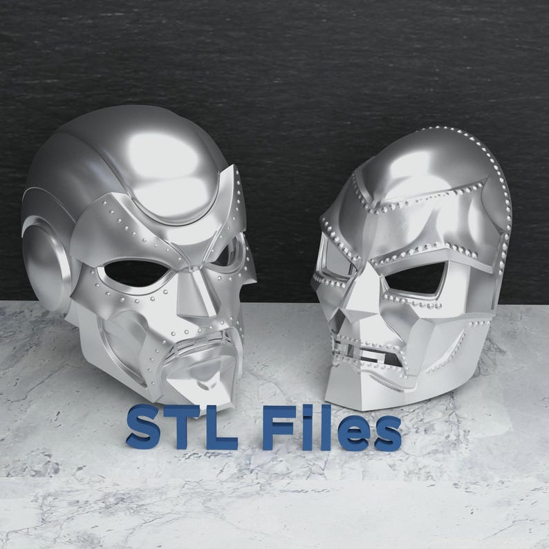 May include: Two silver-colored, futuristic-style masks with rivet details are displayed on a marble surface. The masks are side-by-side, with the text "STL Files" in blue letters at the bottom.