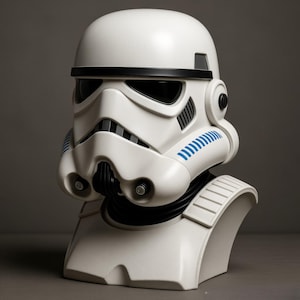 May include: A white Stormtrooper helmet replica with black accents and blue detailing. The helmet features a distinctive design with a black visor, a mouth grill, and a rounded top. The bust is mounted on a white base.