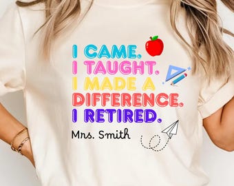 May include: Cream-colored t-shirt with the text "I CAME. I TAUGHT. I MADE A DIFFERENCE. I RETIRED." in colorful letters. Includes a red apple, pencil, and paper airplane graphic. The name "Mrs. Smith" is printed below the text.