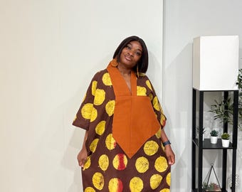 Könnte beinhalten: Ein bodenlanger brauner Kaftan mit einem sich wiederholenden Muster aus gelben Kreisen mit roten Akzenten. Das Kleidungsstück hat einen einfarbigen braunen V-Ausschnitt, weite kurze Ärmel und eine lockere, fließende Silhouette.