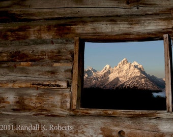 Photograph: Rustic pioneer cabin window view of Tetons.