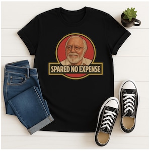 Peut inclure: T-shirt noir avec un portrait dans un cercle rouge et le texte "SPARE NO EXPENSE" dans un rectangle jaune. Le t-shirt est associé à un jean bleu et à des baskets noires et blanches. Une petite plante en pot est également visible.