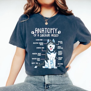 A person wearing a blue t-shirt with a graphic design depicting the anatomy of a Siberian Husky.