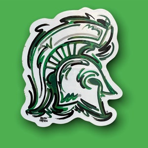 May include: A green and black stylized illustration of a Spartan helmet. The helmet is outlined in black and has a white background. The artist's signature, "Justin Patten", is visible at the bottom of the image.