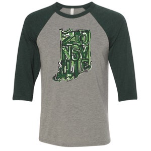 May include: A grey and green baseball t-shirt with a graphic of the state of Indiana with the words "Zionsville" written inside the outline of the state.
