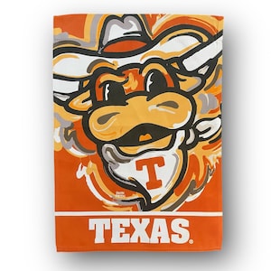 May include: Orange, white, and black garden flag with a cartoon bull mascot wearing a cowboy hat. The bull's face is stylized with a large, toothy grin and the text "TEXAS" is printed below the mascot.