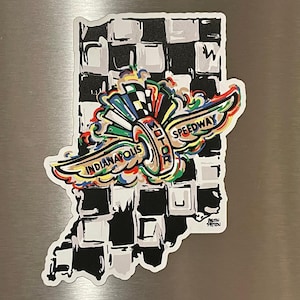 May include: A sticker in the shape of Indiana with a black and white checkered background. The sticker features the words "Indianapolis Motor Speedway" with colorful wings and accents. The artist's signature is in the lower right corner.
