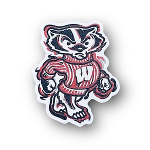 May include: A cartoon illustration of a badger wearing a red and white striped sweater with a white "W" on the front. The badger is standing on its hind legs and has a grumpy expression on its face.