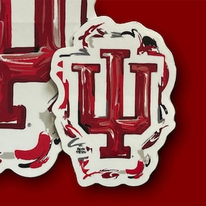 May include: Two white stickers with a red and white abstract design of the letter "I" and the word "IU". The stickers have a white background with a black and gray swirl design around the letters.