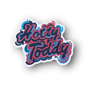 May include: A sticker with the text "Hotty Toddy" in a blue, red, and black font. The sticker has a textured background.